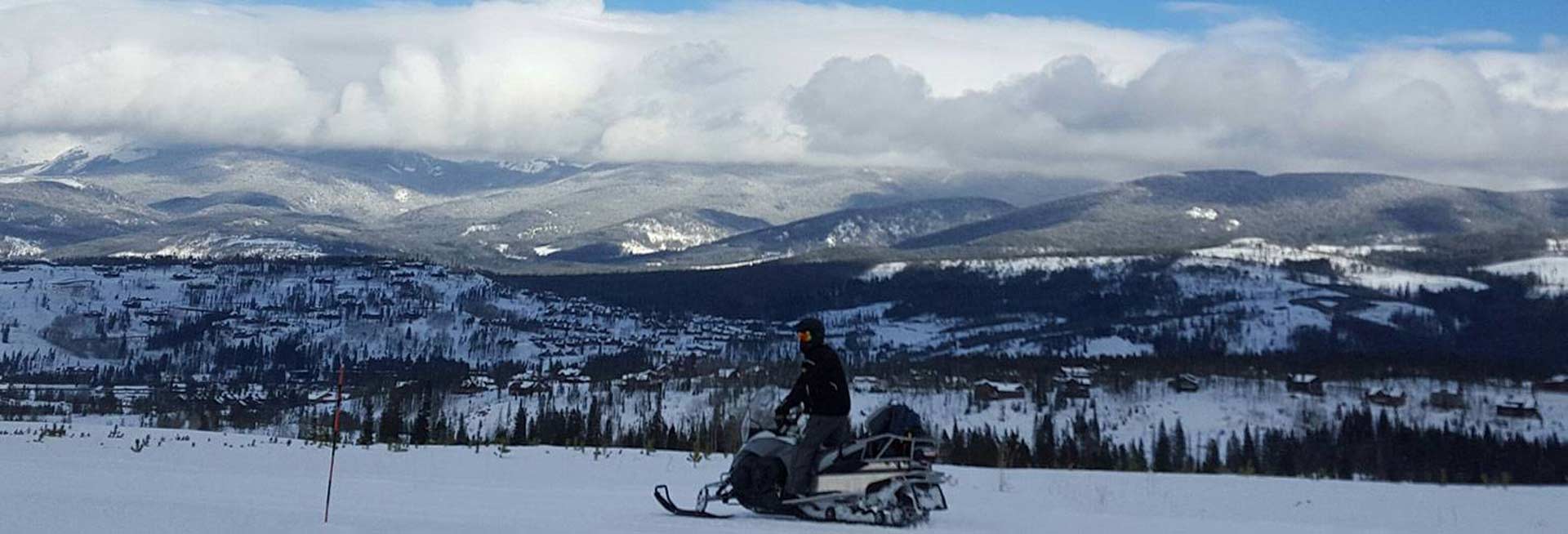 Snowmobiler on the trail overlooking the mountains.