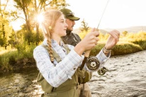 A seasoned fishing guide assists a young female angler.