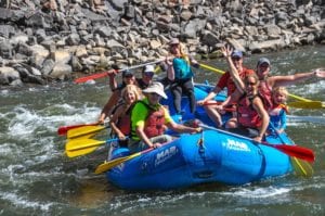 A jovial group of youngsters aboard a white water raft.